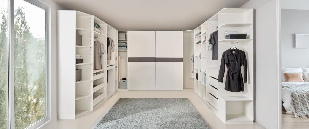 Komplettes Ankleidezimmer perfekt in den Raum eingespasst. Mit vielen Details und über 2 Ecken in Weiß. Mit einer Schiebetür und vielen offenen Fächern