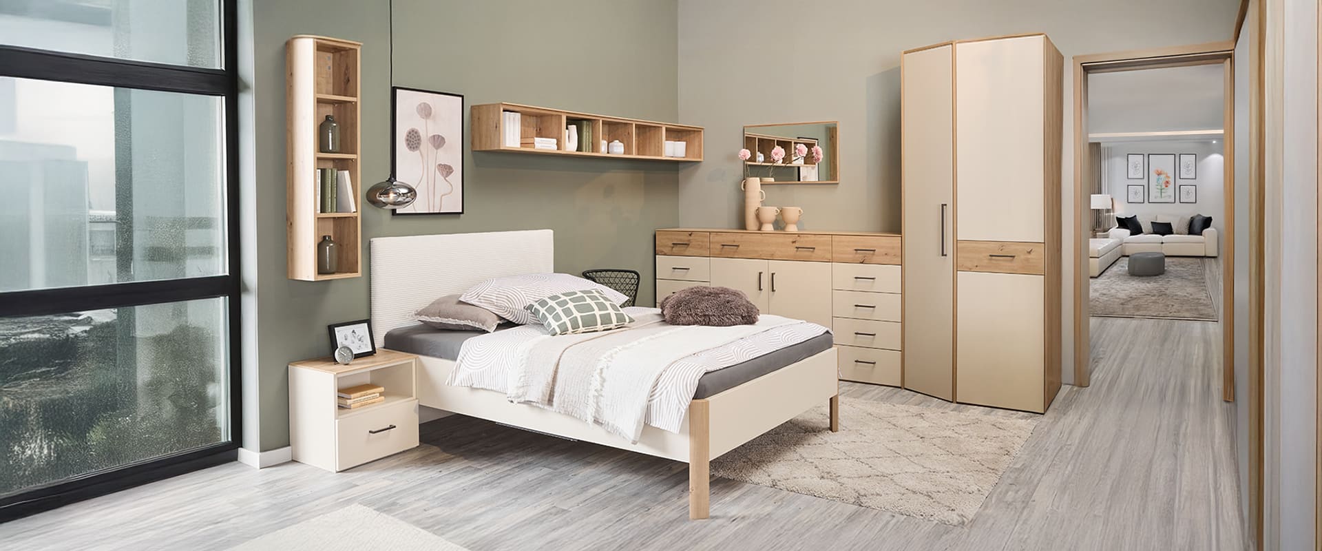 Schlafzimmer mit Bett, Kommode und weiteren Schränken in Artisan Eiche Nachbildung und einer sandfarbigen Front