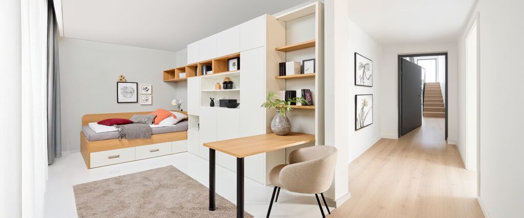 Gästezimmer mit Möbeln vom Fachmann für Sonderanfertigungen. Gästezimmer mit Bett, Regal, Schränken und Tisch in einem Apartment.