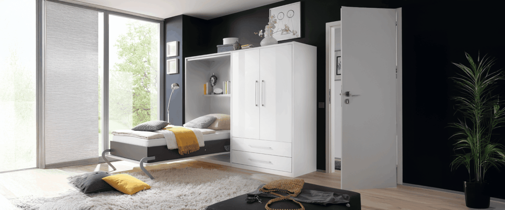 Ein kleine Kombination mit Hochlglanz weißen Fronten bestehend aus einem Wand Klappbett und einem Kleiderschrank. Das Klappbett ist geöffnet
