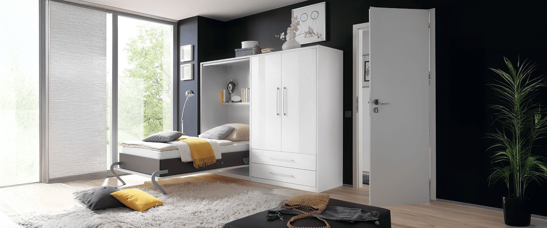 Ein kleine Kombination mit Hochlglanz weißen Fronten bestehend aus einem Wand Klappbett und einem Kleiderschrank. Das Klappbett ist geöffnet