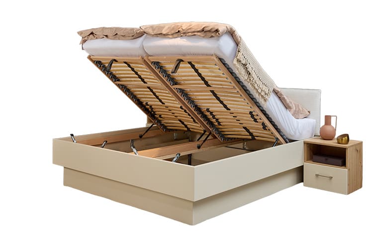 Studio Bett mit zwei geöffneten Doppelbett Studio mit stoffbezogenem Kopfteil und einer Nachtkonsole DeLuxe. Man blickt etwas in den Stauraum. Rechts daneben steht eine Nachkonsolte mit einem Schubkasten und einem offenen Fach