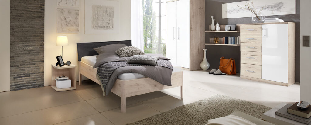 Bett CLASSIC mit vier gerundeten Füßen an jeder Ecke. Das Bett ist bodenfrei und das Bett ist mit einem Kopfteil inkl. Husse im braunen Stoff ausgestattet