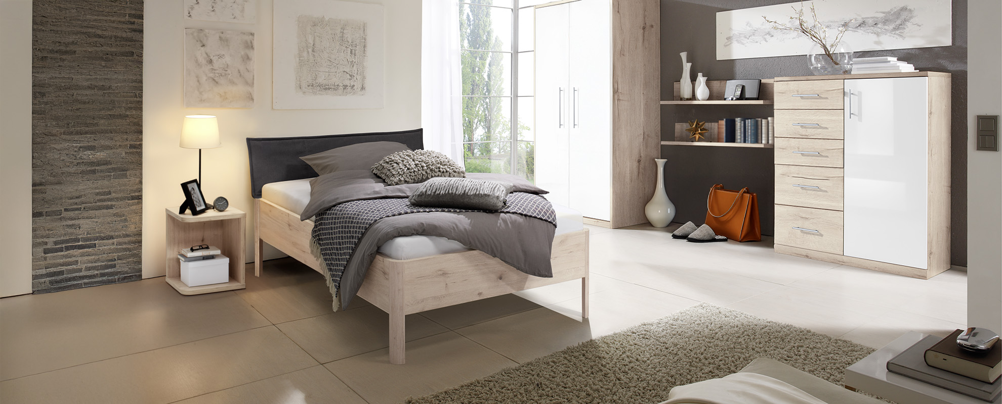 Bett CLASSIC mit vier gerundeten Füßen an jeder Ecke. Das Bett ist bodenfrei und das Bett ist mit einem Kopfteil inkl. Husse im braunen Stoff ausgestattet