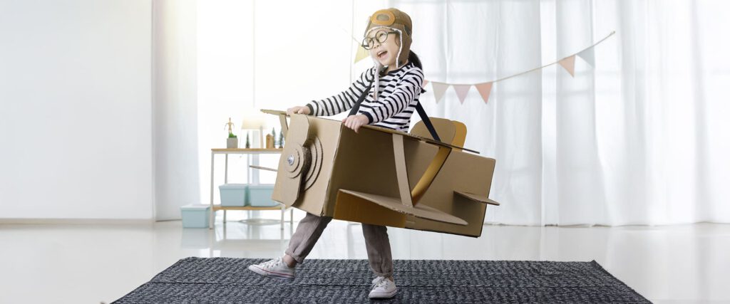 Auf dem Bild sieht man ein Kind, was sich verkleidet hat und sich ein Flugzeug aus Karton gebaut hat. Das steht sinnbildlich für Inspiration. Wir wollen hier die Leute mit unseren Möbeln ebenfalls inspirieren.