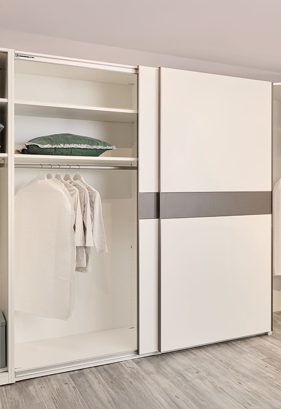 Schwebentürenkleiderschrank mit geöffneten Türen, man blickt in das Innere mit einer Kleiderstange und zwei Böden